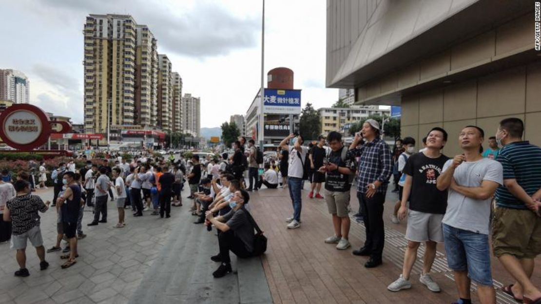 Personas miran hacia la SEG Plaza en Shenzhen después de ser evacuados del tambaleante edificio.