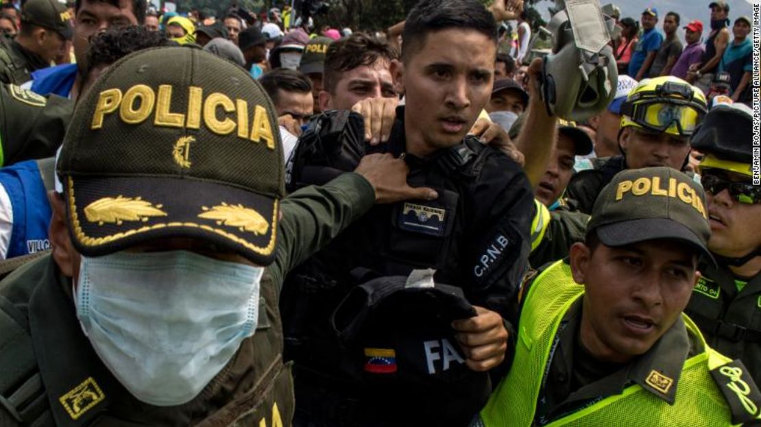 Policías colombianos escoltan a William Cancino González, oficial de las fuerzas especiales de Venezuela, a lo largo de un puente que conecta ambos países, tras la deserción de González.