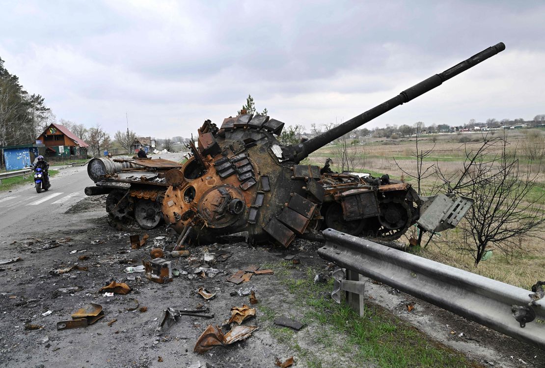 Un hombre en motocicleta pasa junto a un tanque ruso destruido en una carretera en la región de Kyiv el 16 de abril.