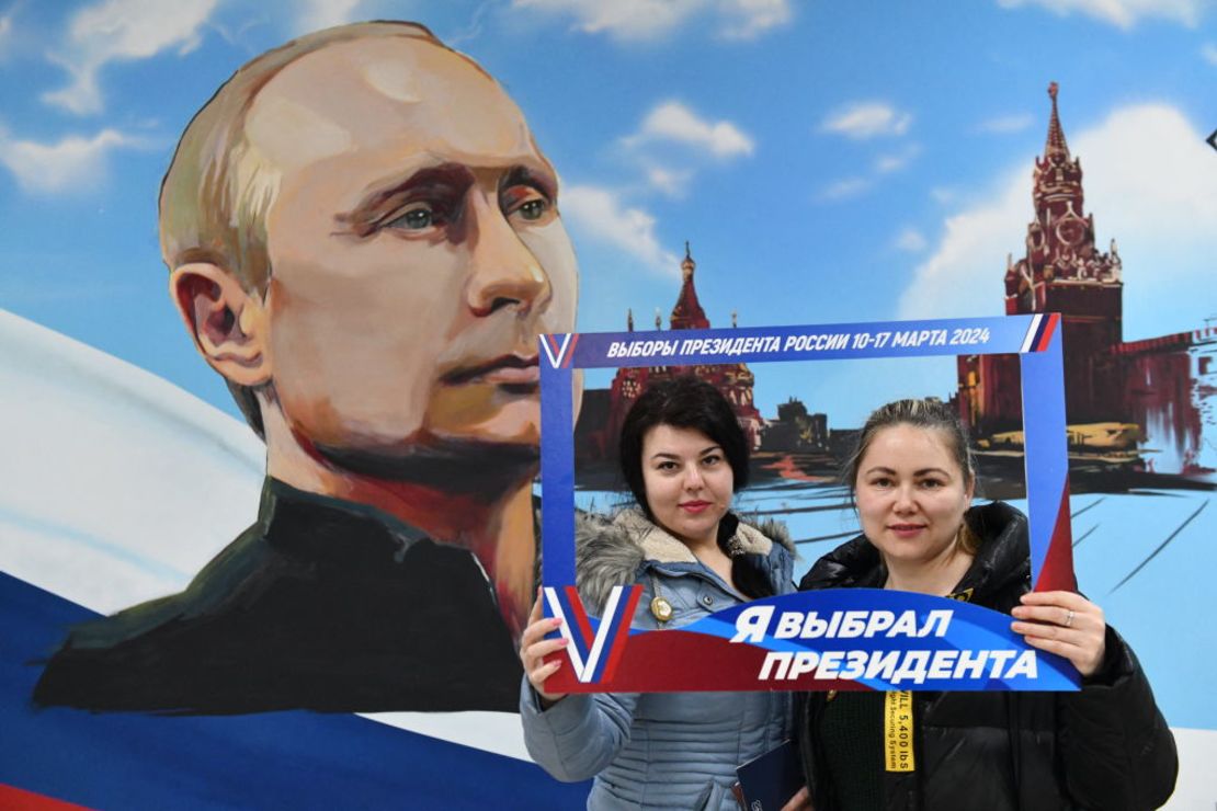 Mujeres posan frente a un mural que representa al presidente Vladimir Putin, después de votar en las elecciones presidenciales de Rusia en un colegio electoral en una escuela local en Donetsk, en los territorios de Ucrania controlados por Rusia, el 15 de marzo de 2024.