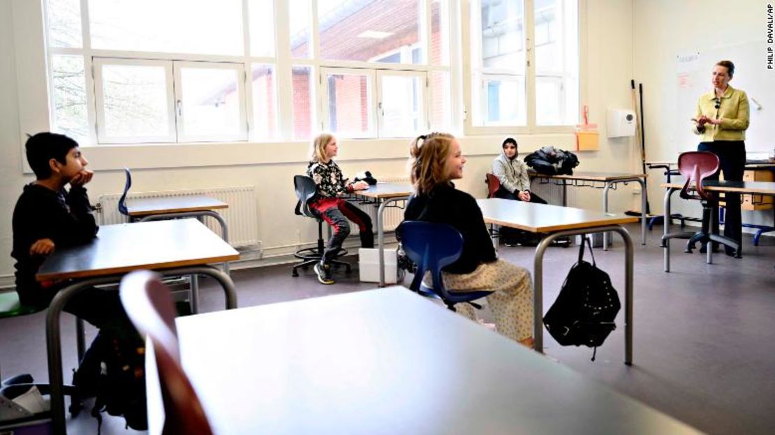 La primera ministra de Dinamarca, Mette Frederiksen, a la derecha, habla con estudiantes que están sentados a dos metros uno del otro durante la reapertura de la Escuela Lykkebo en Copenhague.