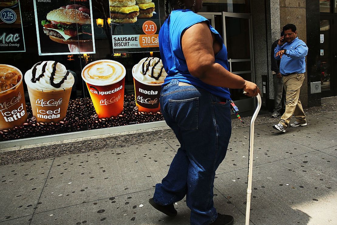 Una mujer camina frente a un cartel de bebidas azucaradas en Brooklyn, Nueva York, en 2013.