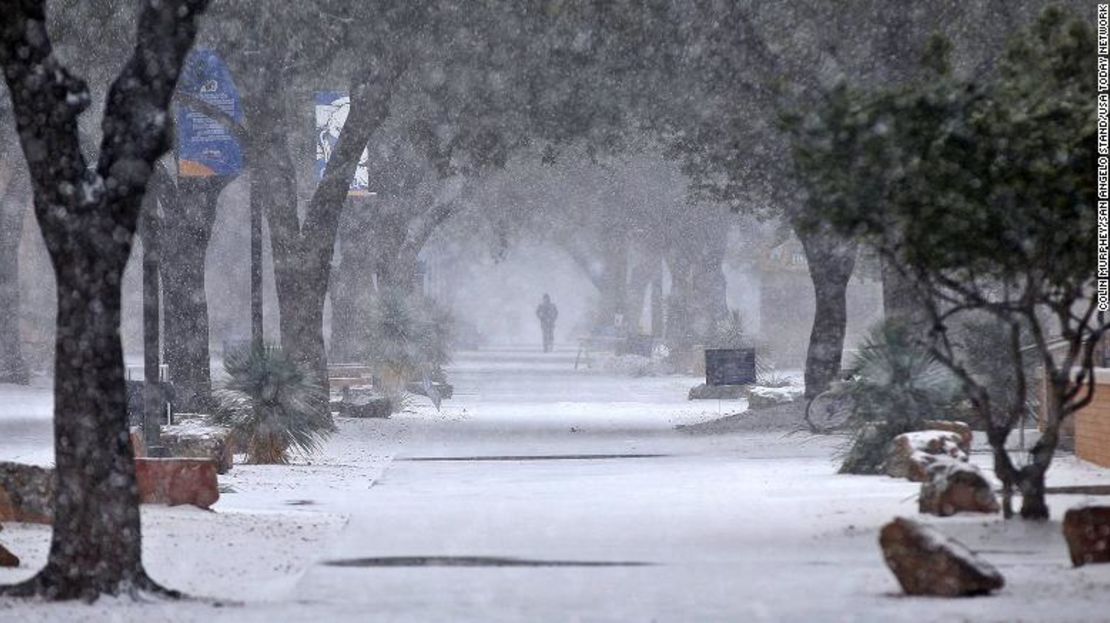 Un peatón camina entre la nieve en la Angelo State University en Texas.