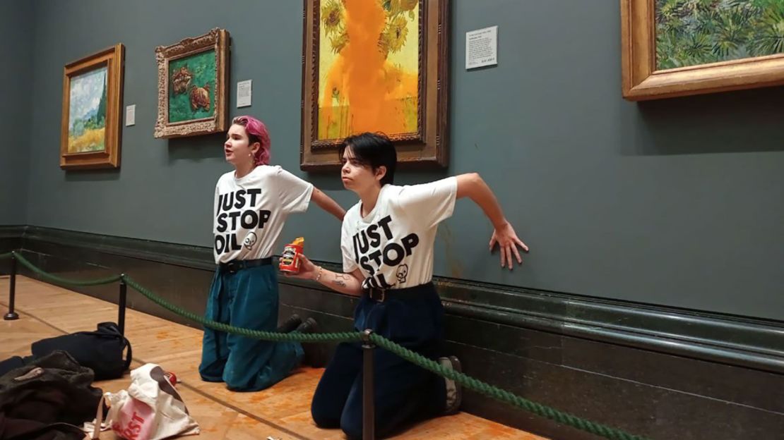 En esta imagen difundida por la organización Just Stop Oil, se ve a dos mujeres de pie frente a "Girasoles" de Van Gogh (1888). Crédito: de Just Stop Oil