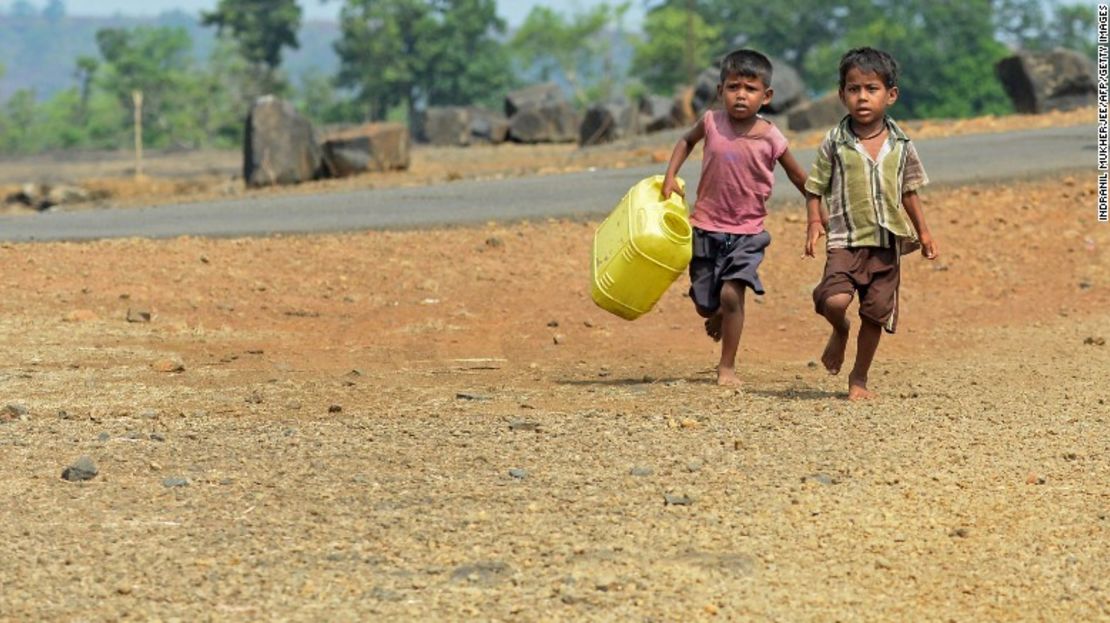 Dos pequeños corren hacia un pozo de agua en Shahapur, India, país en donde se registran altas temperaturas que están rompiendo récords históricos.