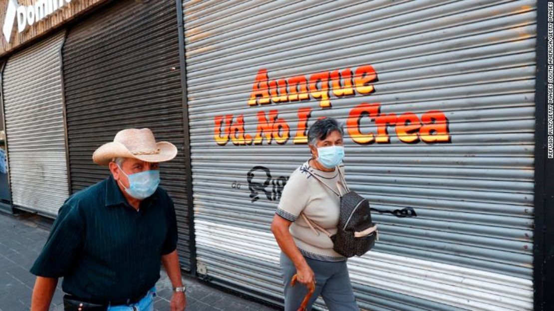 Gente camina frente a una tienda cerrada en Guadalajara.