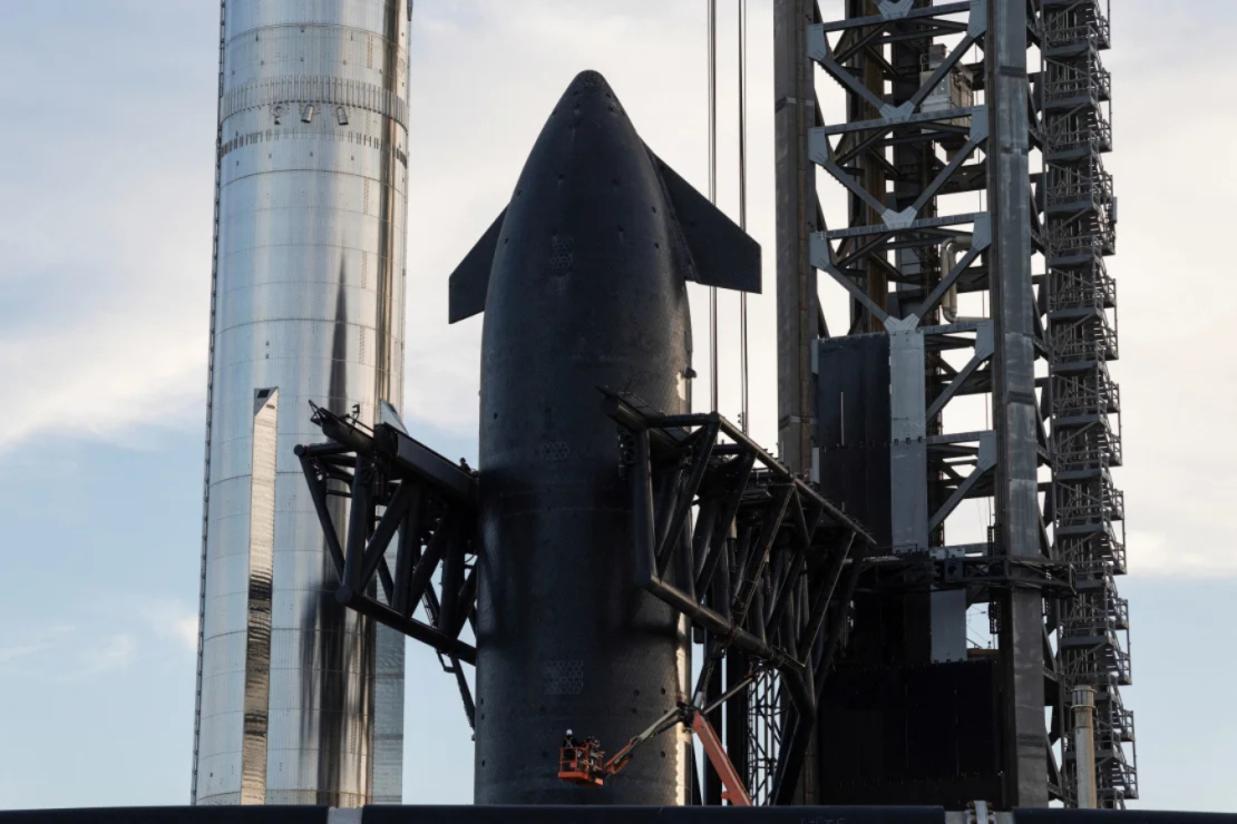 El propulsor Super Heavy (izquierda) se ve junto a la nave espacial Starship, o etapa superior (derecha), que está asegurada en los brazos de la torre de lanzamiento en las instalaciones de Starbase cerca de Brownsville, Texas, el domingo.