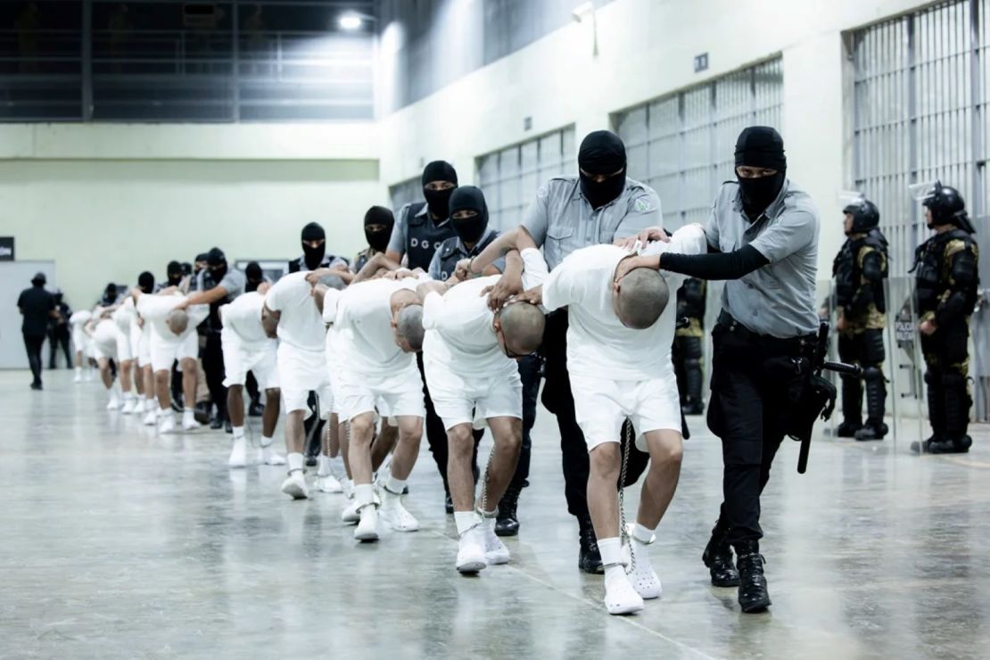 En esta foto proporcionada por la oficina de prensa de la presidencia de El Salvador, guardias penitenciarios trasladan a deportados de EE.UU., presuntos pandilleros venezolanos, al Centro de Reclusión Antiterrorista en Tecoluca, El Salvador, el 16 de marzo de 2025.