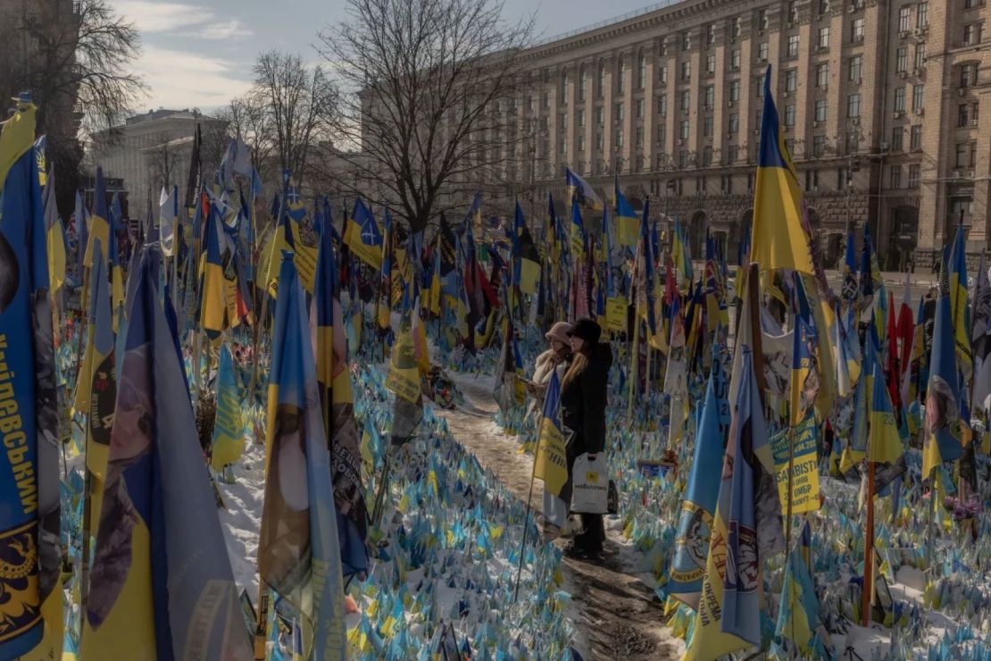 Visitantes se acercan a un memorial improvisado en homenaje a combatientes ucranianos y extranjeros en la Plaza de la Independencia de Kyiv, antes del tercer aniversario de la invasión de Ucrania por parte de Rusia.