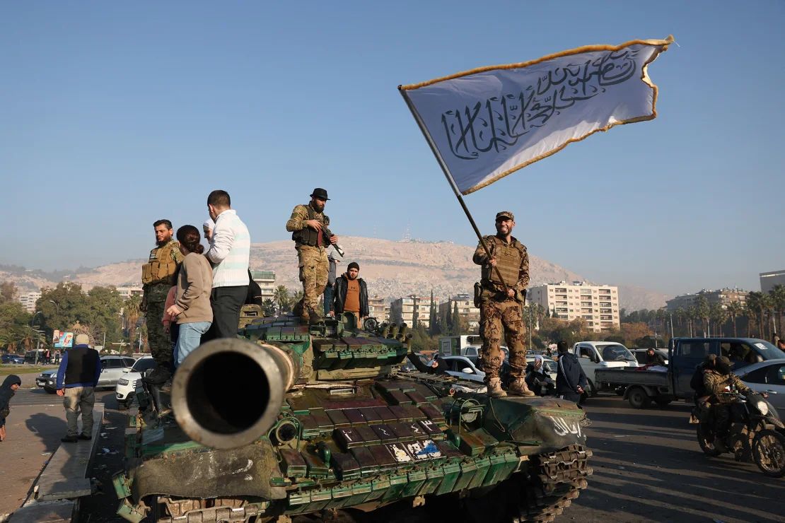 Un combatiente antigubernamental ondea una bandera islámica desde lo alto de un tanque en Damasco, Siria, el 9 de diciembre.