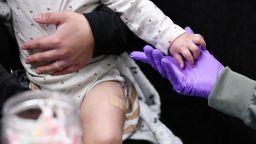 Sherry Andrews sostiene la mano de un niño de 13 meses tras istrarle su primera dosis de vacuna triple vírica en Lubbock, Texas, el 27 de febrero.