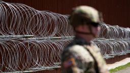 Un miembro del ejército observa frente a un alambre de púas recién instalado que recubre uno de los dos muros fronterizos que separan México de Estados Unidos durante una conferencia de prensa sobre operaciones conjuntas en las que participan el ejército y la Patrulla Fronteriza, el 21 de marzo en San Diego.