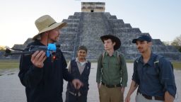 MrBeast y su equipo junto a una persona con chaleco del INAH a las afueras de la pirámide de Kukulkán, en la zona arqueológica de Chichén Itzá.