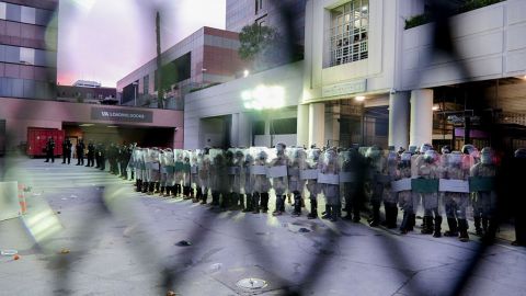 Esta imagen muestra a la policía antidisturbios a través de una valla de seguridad mientras se alinea afuera del Centro de Detención Metropolitano, en el centro de Los Ángeles el 1 de septiembre de 2025, momentos antes de arrestar a manifestantes.