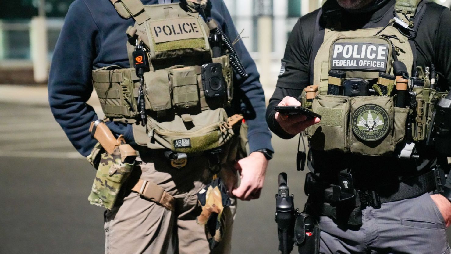 En esta foto facilitada por el ICE de EE.UU., dos agentes de las fuerzas federales de seguridad se coordinan con otros funcionarios sobre el terreno durante una operación reforzada de control de inmigración el 4 de febrero de 2025 cerca de la ciudad de Washington.
