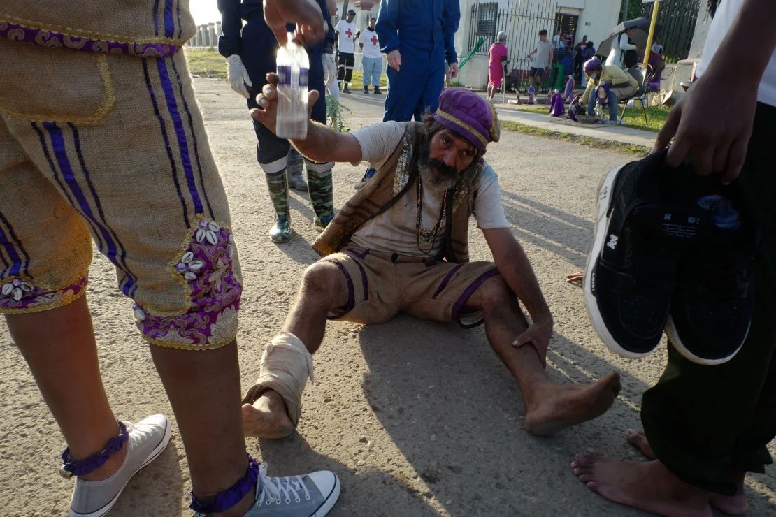 Un peregrino acepta agua de los médicos mientras gatea hacia atrás para honrar a San Lázaro.