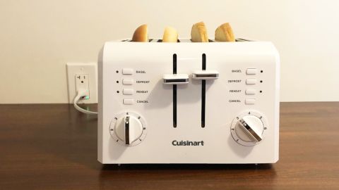 A white Cuisinart 4-Slice Compact Toaster on a wooden counter, toasting 2 bagels.