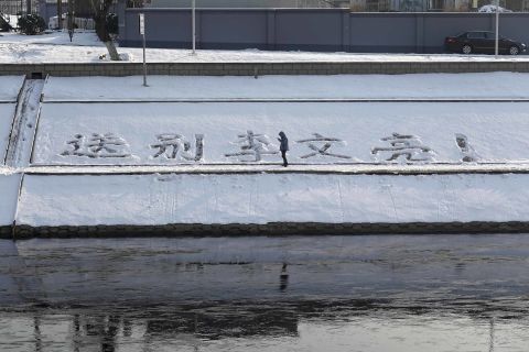 A man stops by a message drawn into the snow that reads, "Farewell to Li Wenliang" in Beijing on Friday.