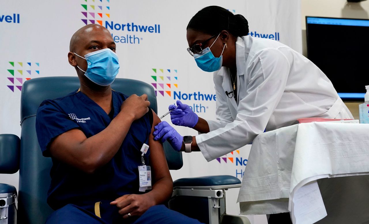Dr. Yves Duroseau, chair of emergency medicine at Lenox Hill Hospital, is administered the Pfizer-BioNTech Covid-19 vaccine by Dr. Michelle Chester in Queens, New York, on December 14.