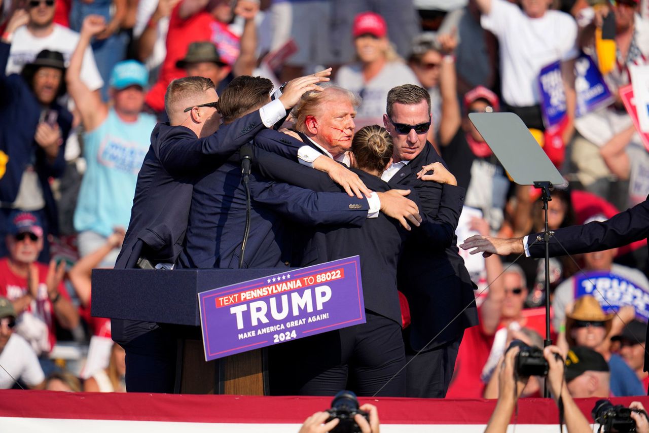 Former President Donald Trump is surrounded by Secret Service agents after a gunman fired multiple shots, including one that Trump says hit him in the ear, at a campaign event in Butler, Pennsylvania, on July 13.