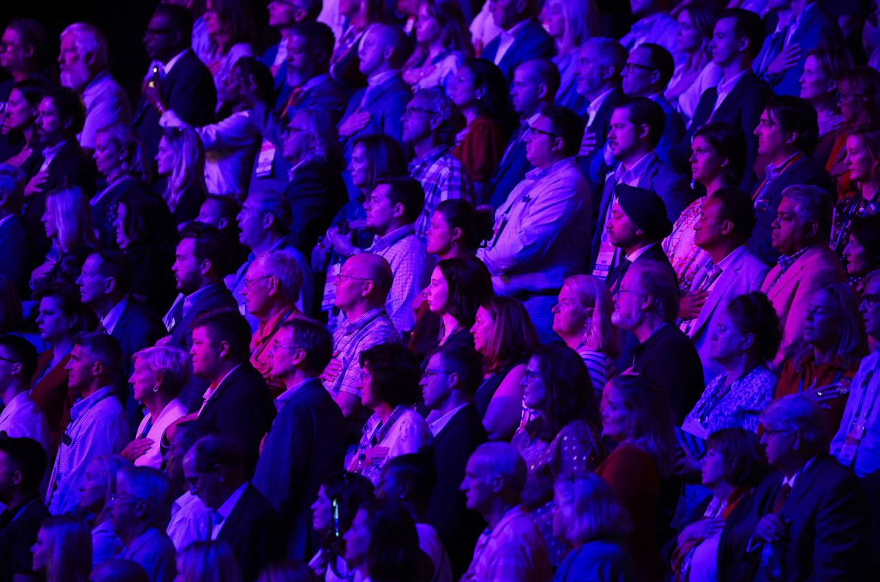 Debate attendees stand for the Pledge of Allegiance.