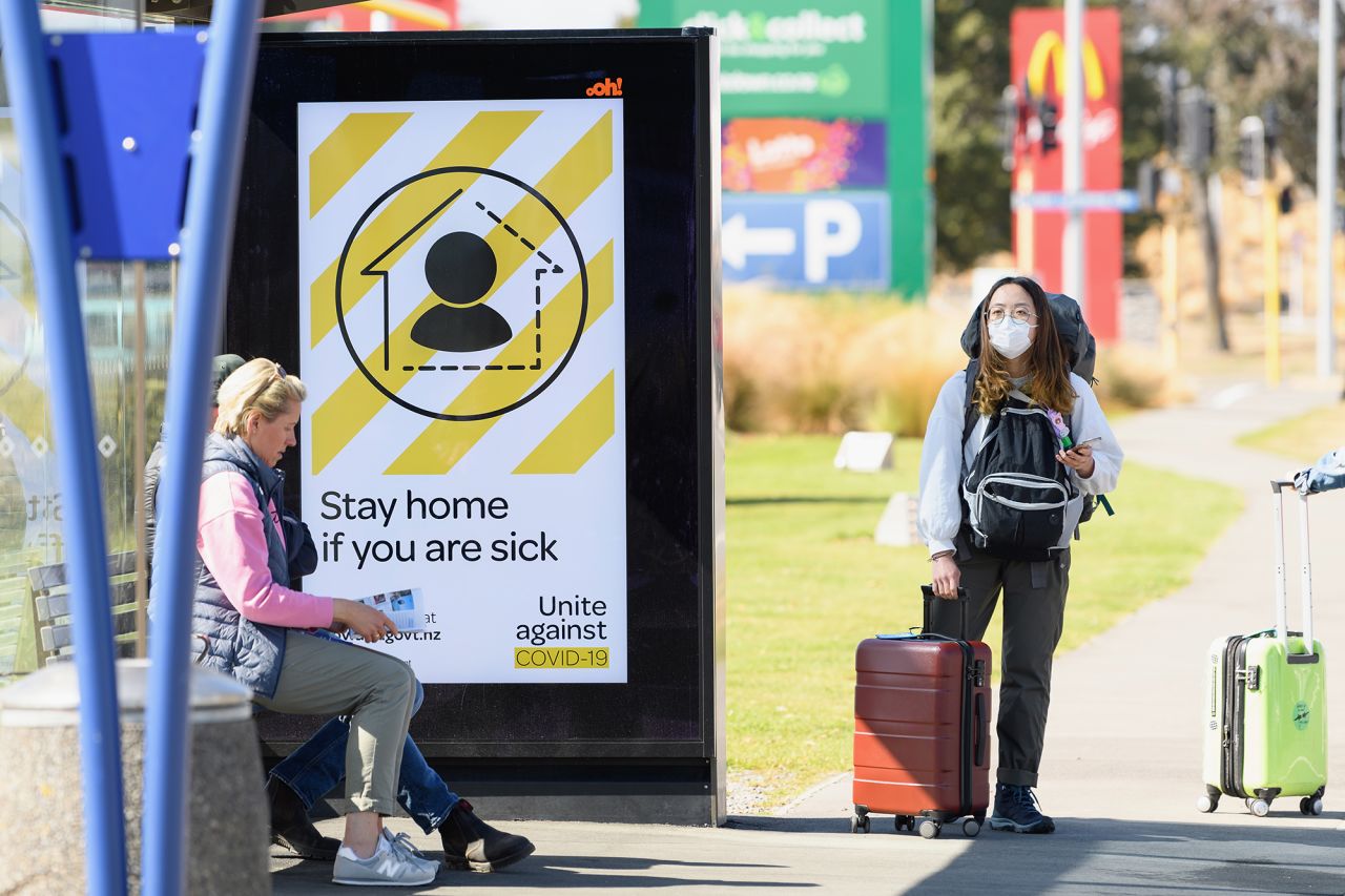 A traveler wearing a protective mask is seen waiting for a bus near Christchurch International Airport on March 18, in Christchurch, New Zealand.