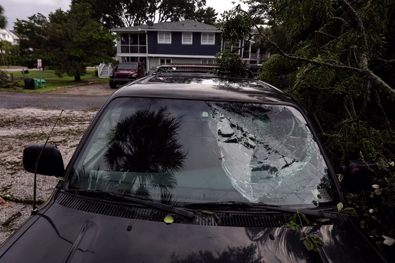 A palm tree is reflected in a car's broken windshield in Isle of Palms, South Carolina, on August 6.