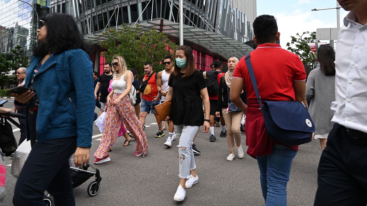 A pedestrian wearing protective face mask cross the road in Singapore.\n