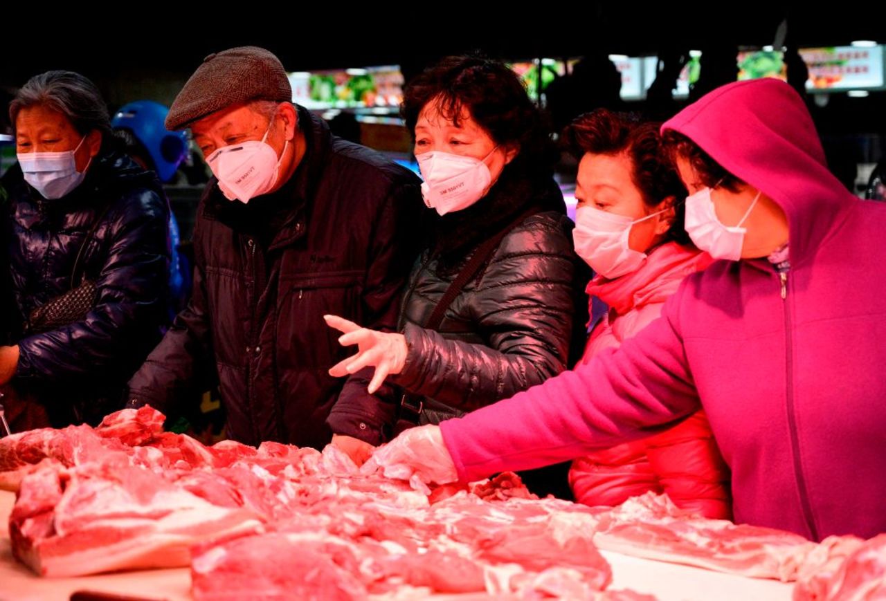 People wearing protective face masks shop for meat at a market in Shanghai on February 14, 2020.