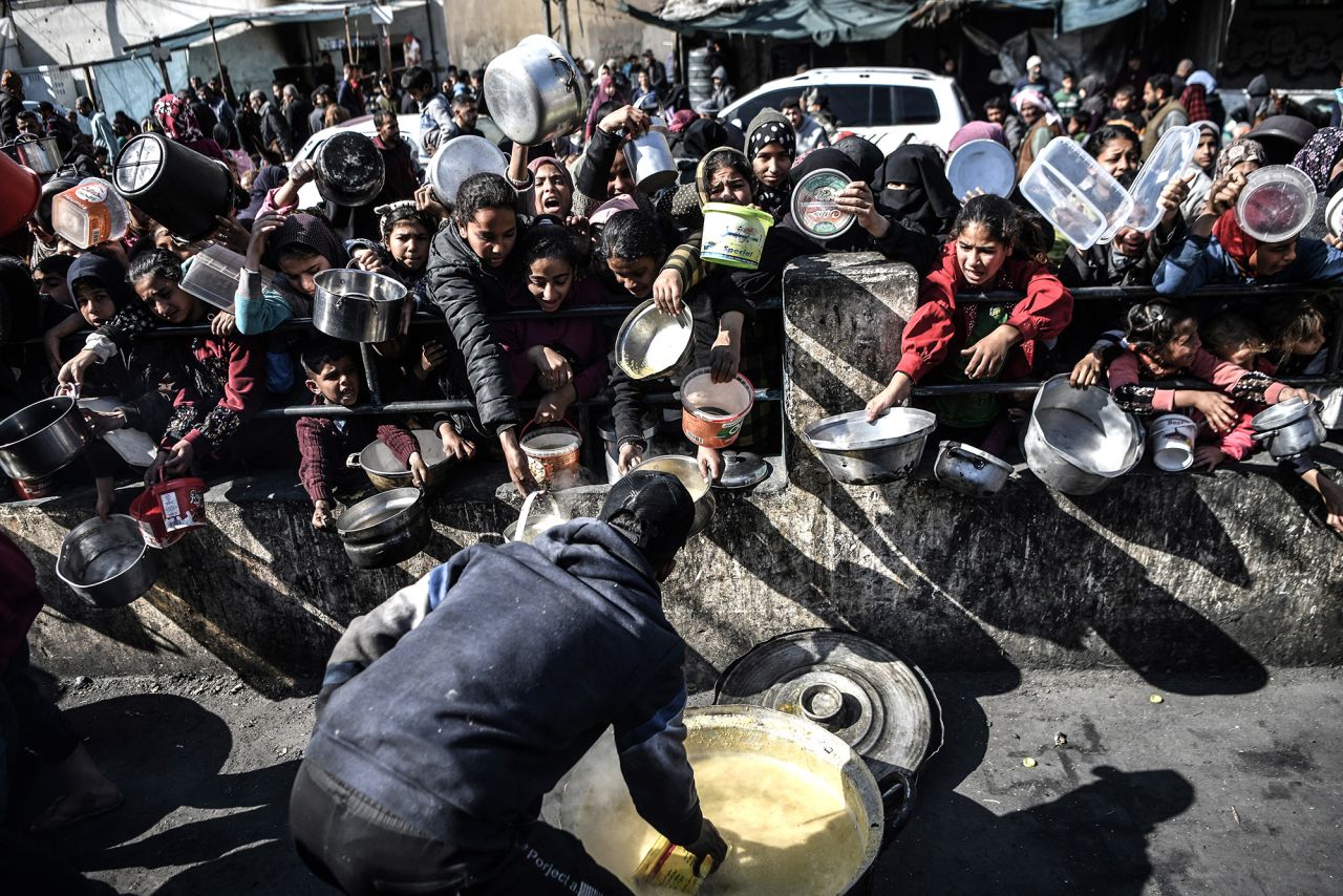 Palestinian people wait with empty containers as food is distributed by charitable organizations in Rafah, Gaza, on January 25.