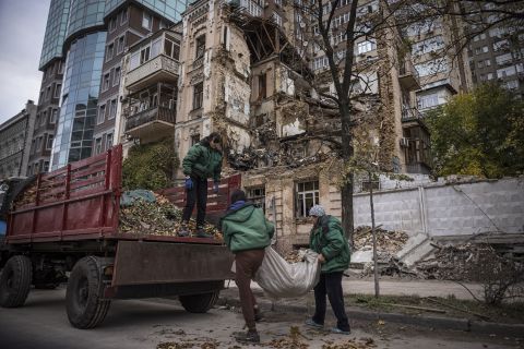 People clear blast debris outside a house damaged during a Russian drone strike on October 19, in Kyiv, Ukraine. 