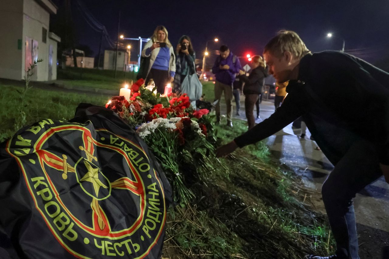 A man places flowers at a makeshift memorial near PMC Wagner Center in St. Petersburg, Russia, on August 24.