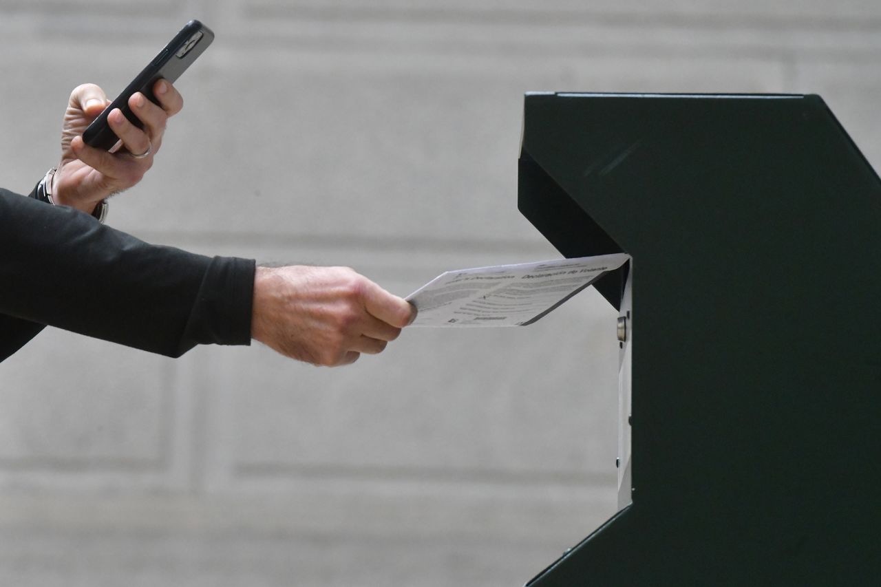 A man photographs himself depositing his ballot in an official ballot drop box while a long line of voters queue outside of Philadelphia City Hall at the satellite polling station on October 27, in Philadelphia, Pennsylvania. 