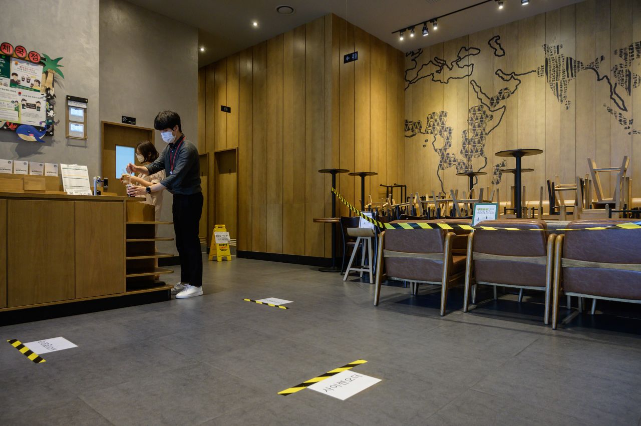 Customers wearing face masks collect their orders as chairs and tables are stacked together as part of social distancing efforts inside a cafe in Seoul, on August 31. 