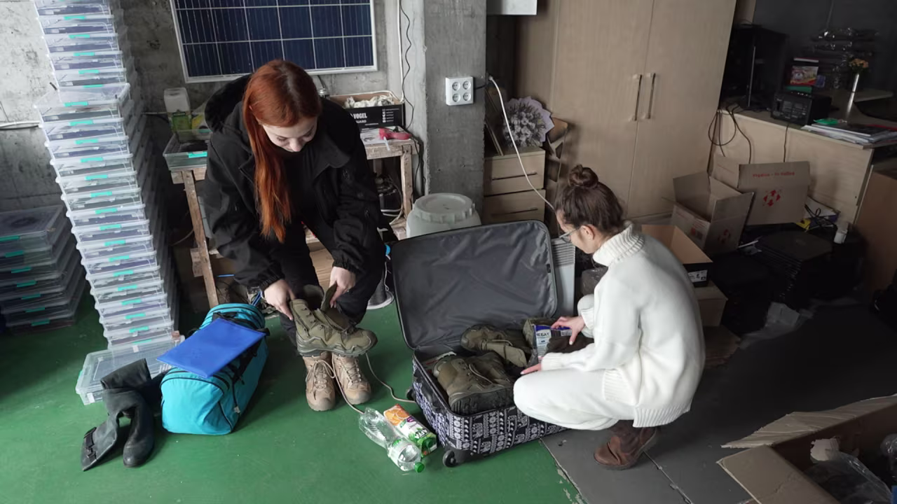 Twenty-one-year-old Roksolana, left, tries on her new boots while Kseniia Drahanyuk, the co-founder of the Zemlyachki NGO, helps her fill a suitcase with all kinds of items.