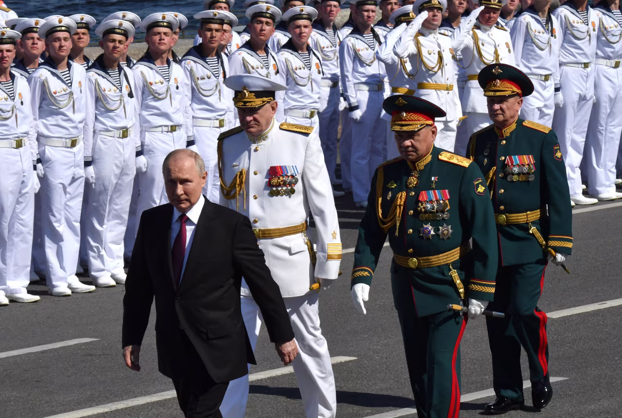 Russian President Vladimir Putin, accompanied by Defence Minister Sergei Shoigu and Commander-in-Chief of the Russian Navy, Admiral Nikolai Yevmenov, attends the Navy Day parade in Saint Petersburg on July 30.