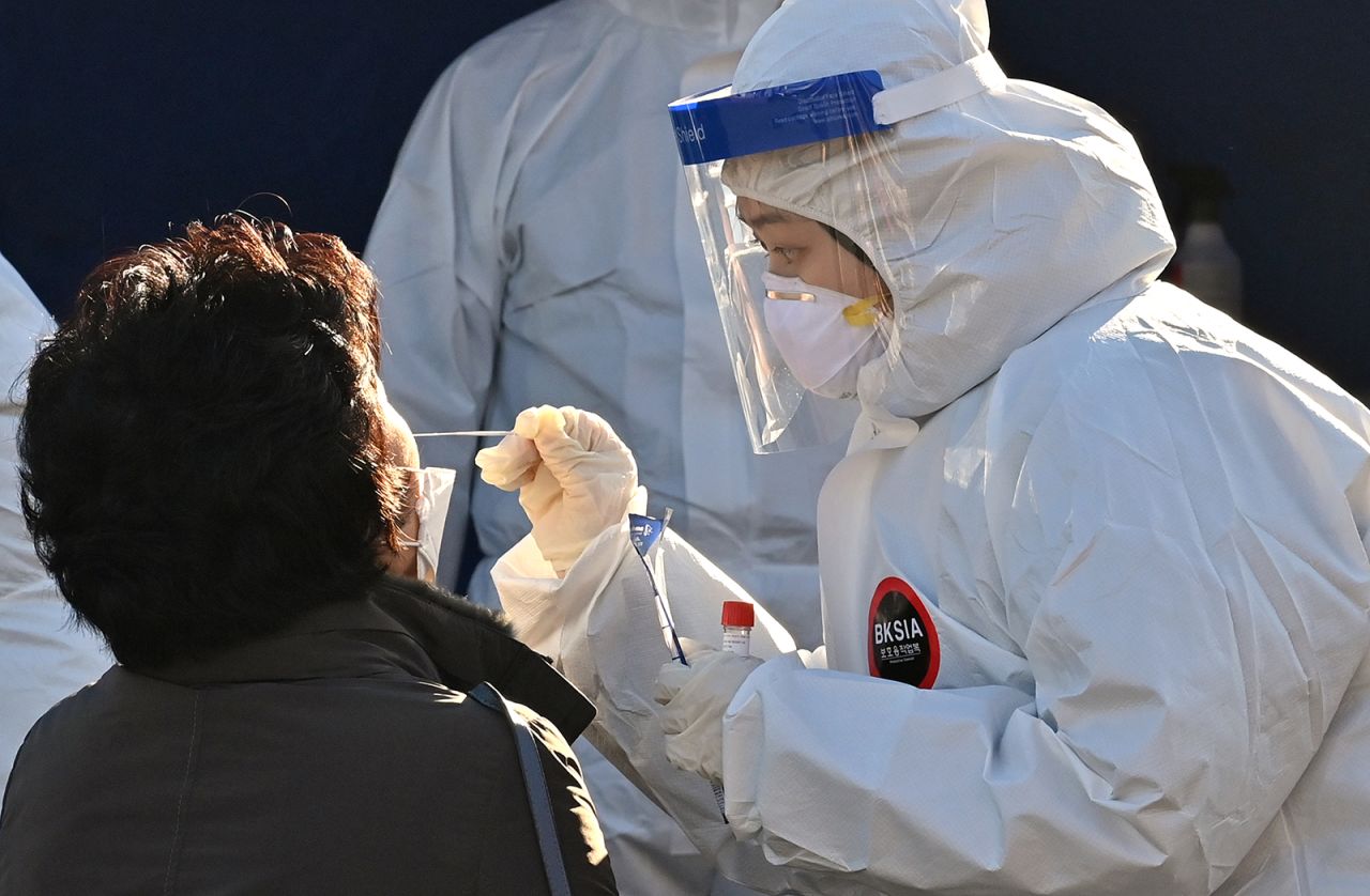 A medical staff member wearing protective gear takes a swab from a woman to test for Covid-19 at a temporary testing station in Seoul, South Korea, on Dec. 14.