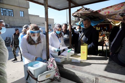 Health care workers are seen at a market in Baghdad, Iraq, during a campaign to detect coronavirus infections on January 31.