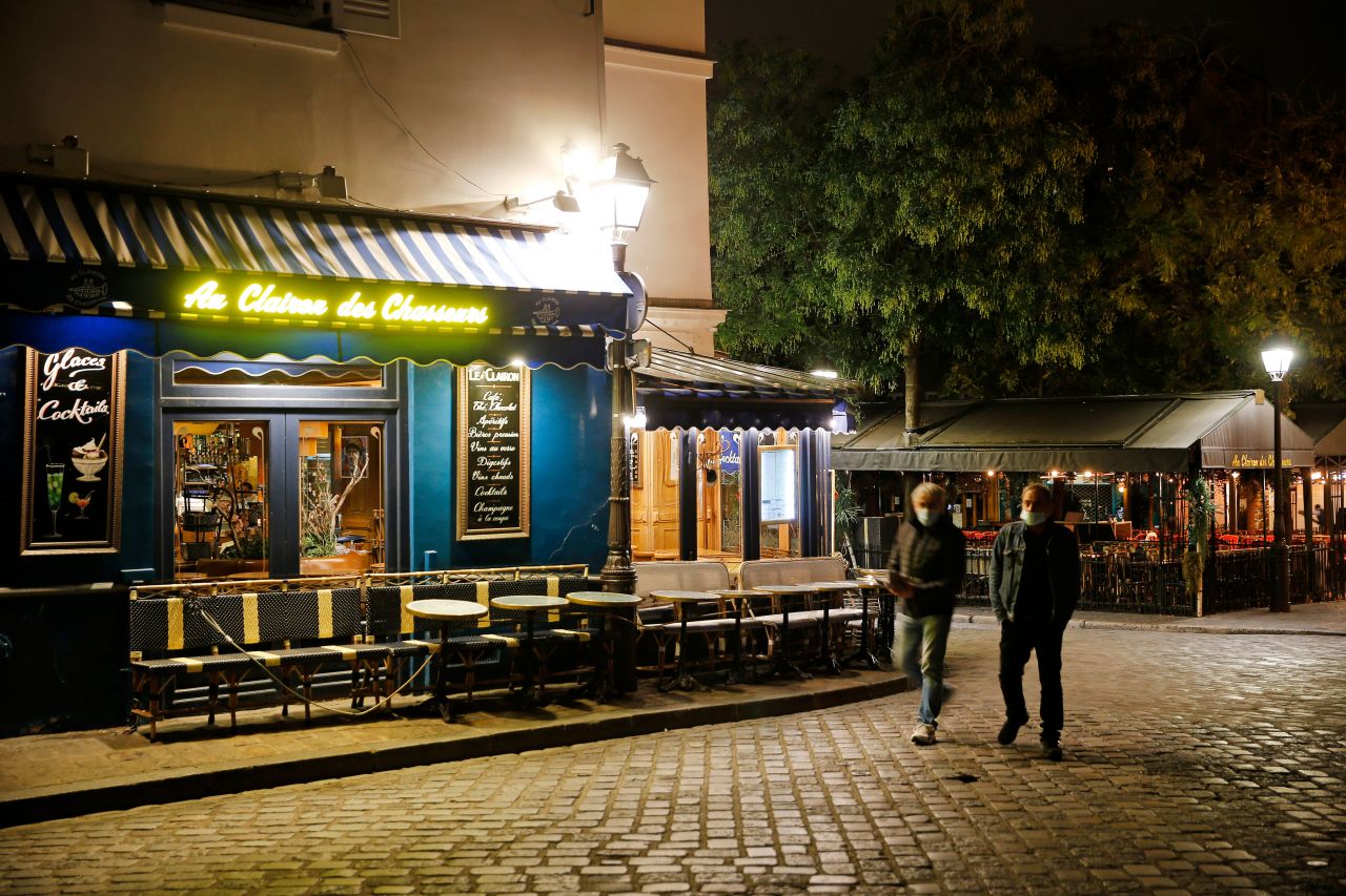 Men walk past empty restaurants at Place du Tertre in Paris on October 15.