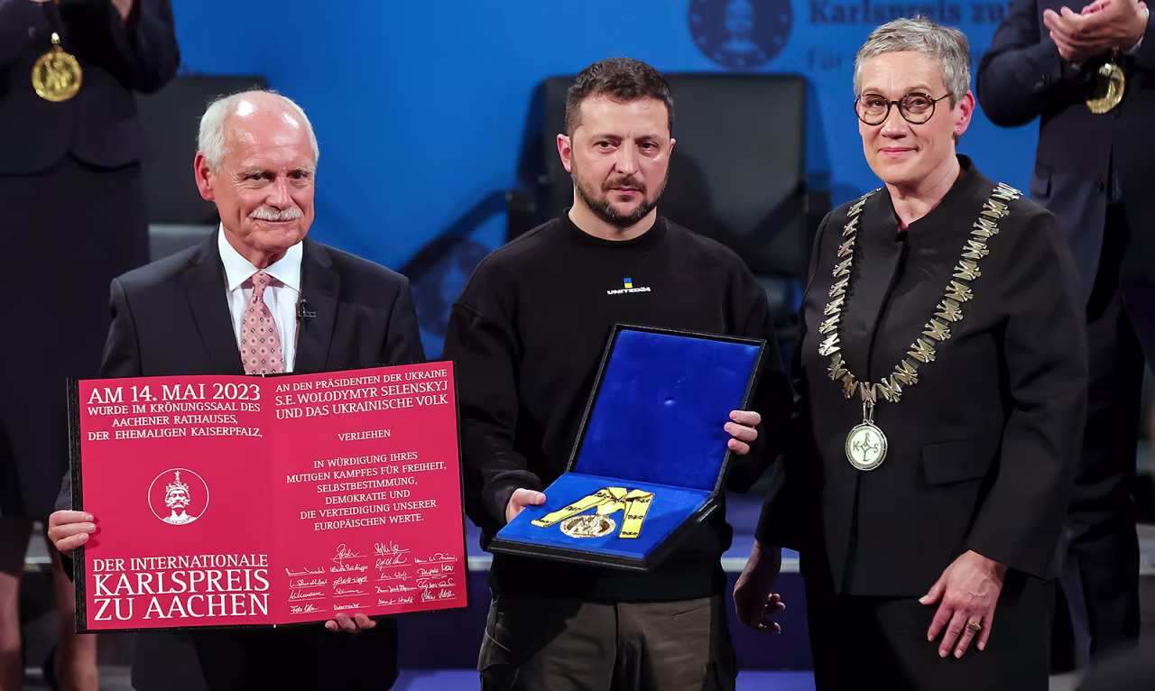 Ukrainian President Volodymyr Zelensky, center, holds the Charlemagne Prize on May 14, in Aachen, Germany. 