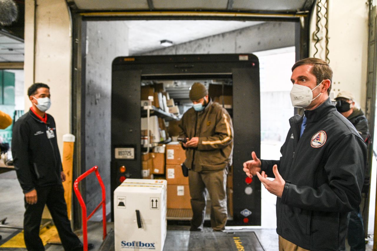 Kentucky Governor Andy Beshear, right, speaks to the media as Byron Bishop, a UPS driver, scans a delivered COVID-19 vaccination package in a loading dock at University of Louisville Hospital on December 14 in Louisville, Kentucky. 