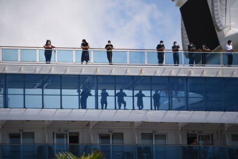 Passengers look out from the deck of the Coral Princess cruise ship as it docks in Miami, Florida, on April 4.