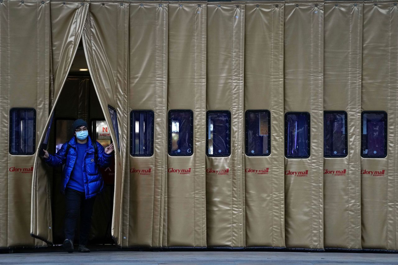 A man wearing a face mask to help curb the spread of the coronavirus walks out from a shopping mall in Beijing, Nov. 29, 2021.