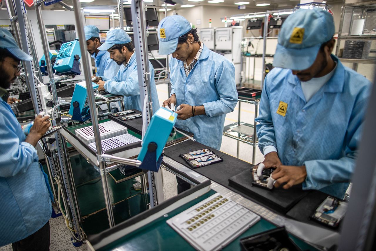 Employees work on a mobile phone assembly line at a subsidiary of Dixon Technologies in Noida, India. 