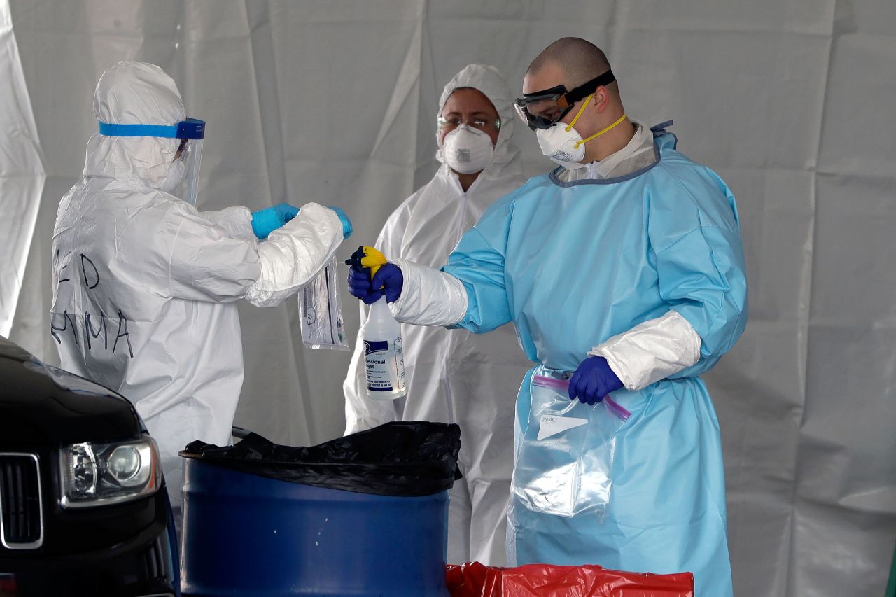 Medical workers spray a bag containing a coronavirus test at a drive-through testing site in Foxborough, Massachusetts, on April 5.