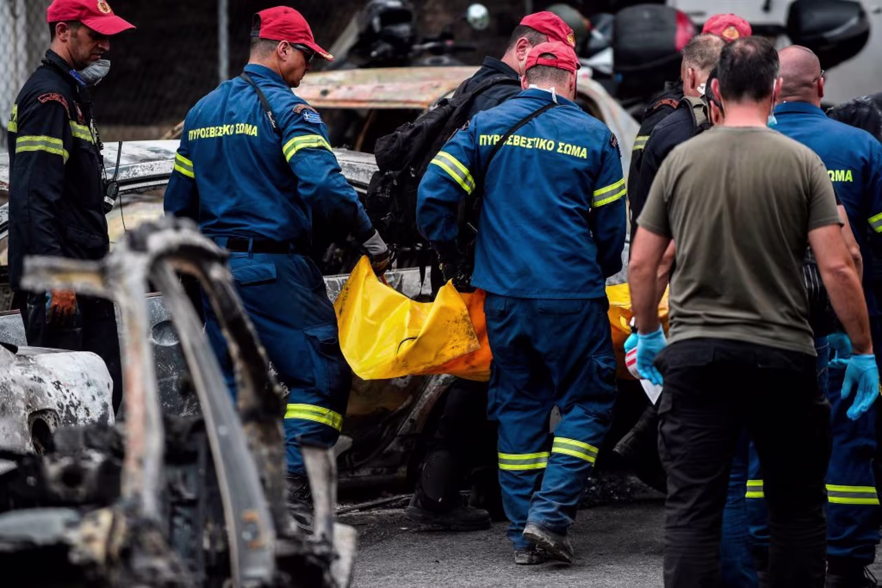 Rescuers carry a body bag following a wildfire that tore through the village of Mati, near Athens, on July 24, 2018.