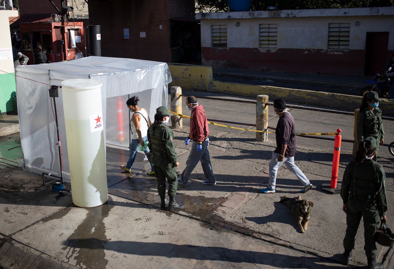 People go through a decontamination chamber as a preventive measure against the spread of the coronavirus, before entering a popular market in Caracas, Venezuela, on Wednesday, March 18. 