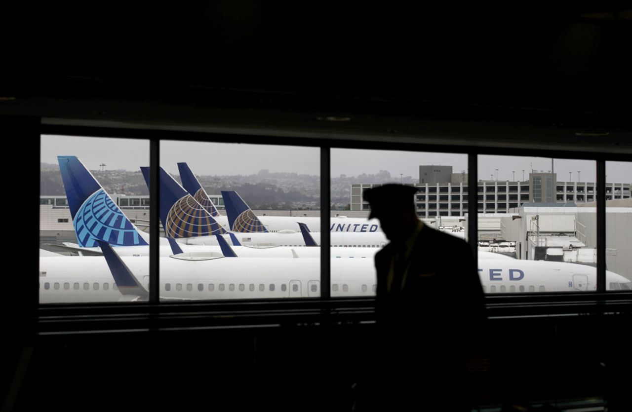 A pilot walks by United Airlines planes as they sit parked at gates at San Francisco International Airport on April 12, in San Francisco, California.