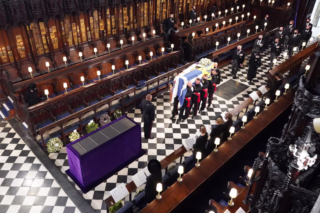 Queen Elizabeth II, left, watches as pallbearers carry Prince Philip’s coffin during his funeral inside St. George's Chapel in Windsor Castle, on April 17.