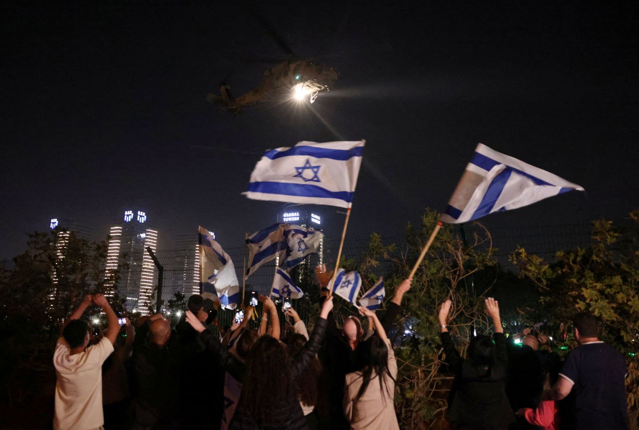 People wave Israeli flags as helicopter carrying hostages released by Hamas arrives at Schneider Children's Medical Center in Petah Tikva, Israel, on Friday. 